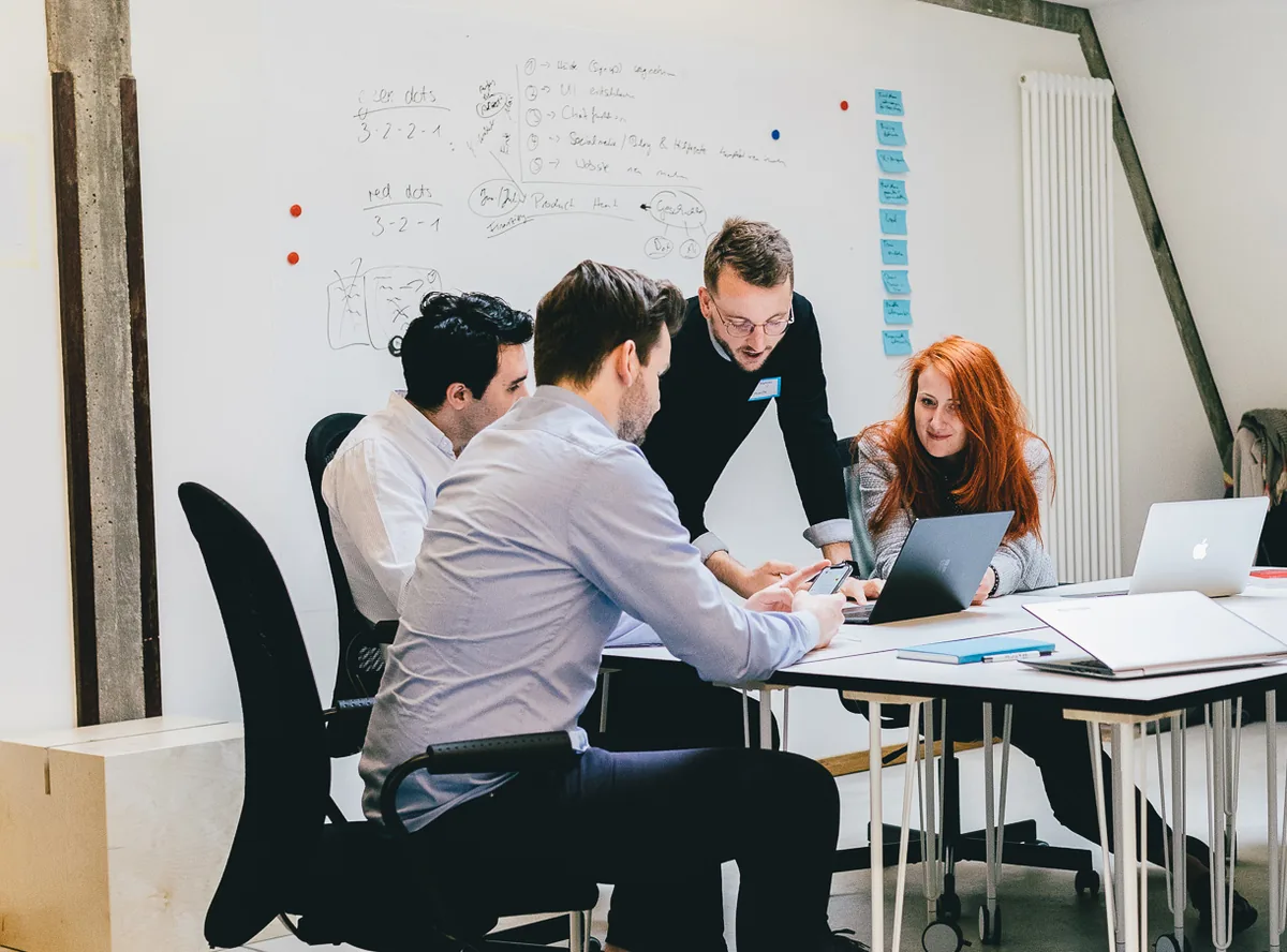 Founders working together at a table in front of a whiteboard